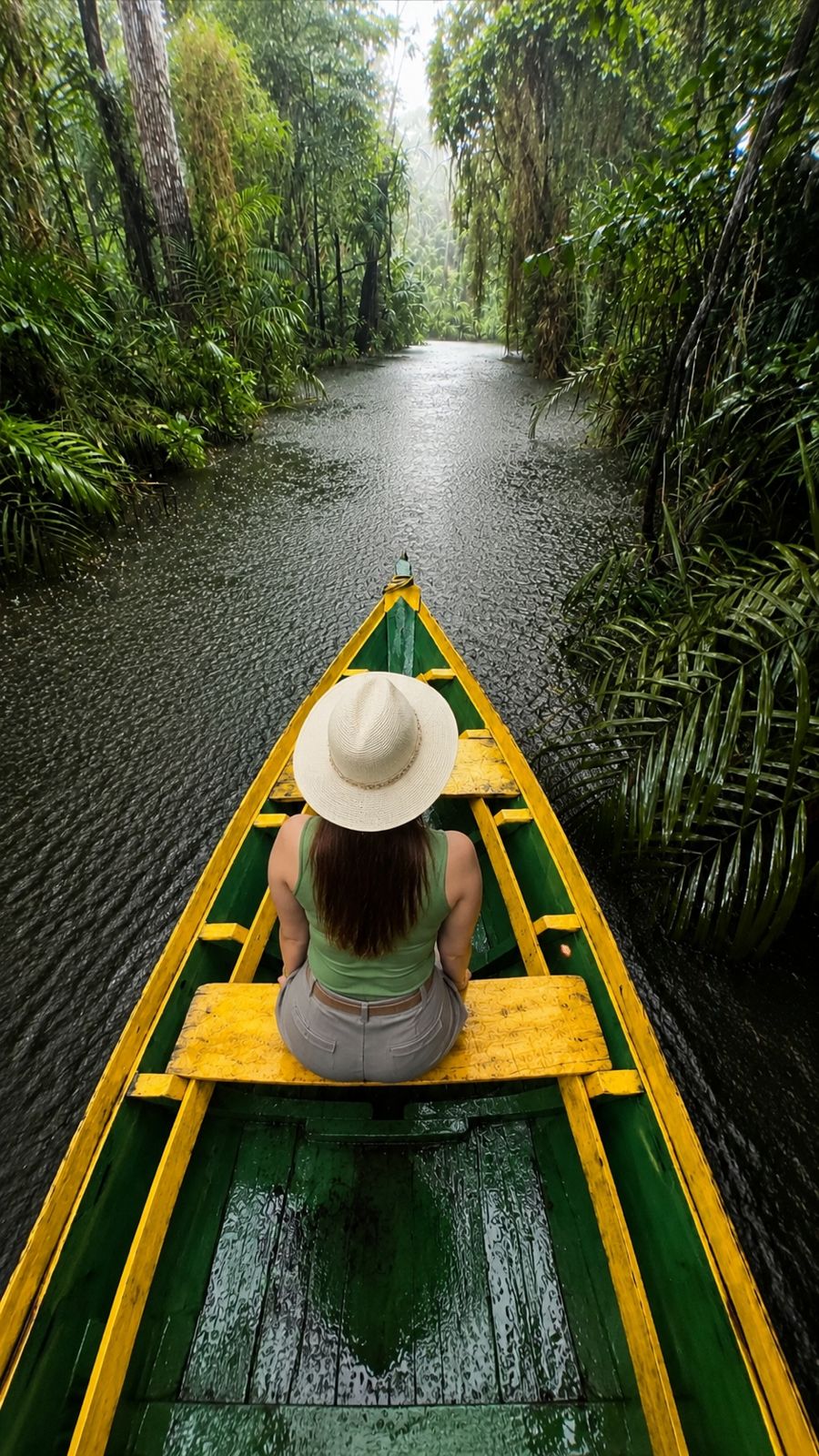 Viajante em canoa de madeira navegando por igarapé cercado de floresta