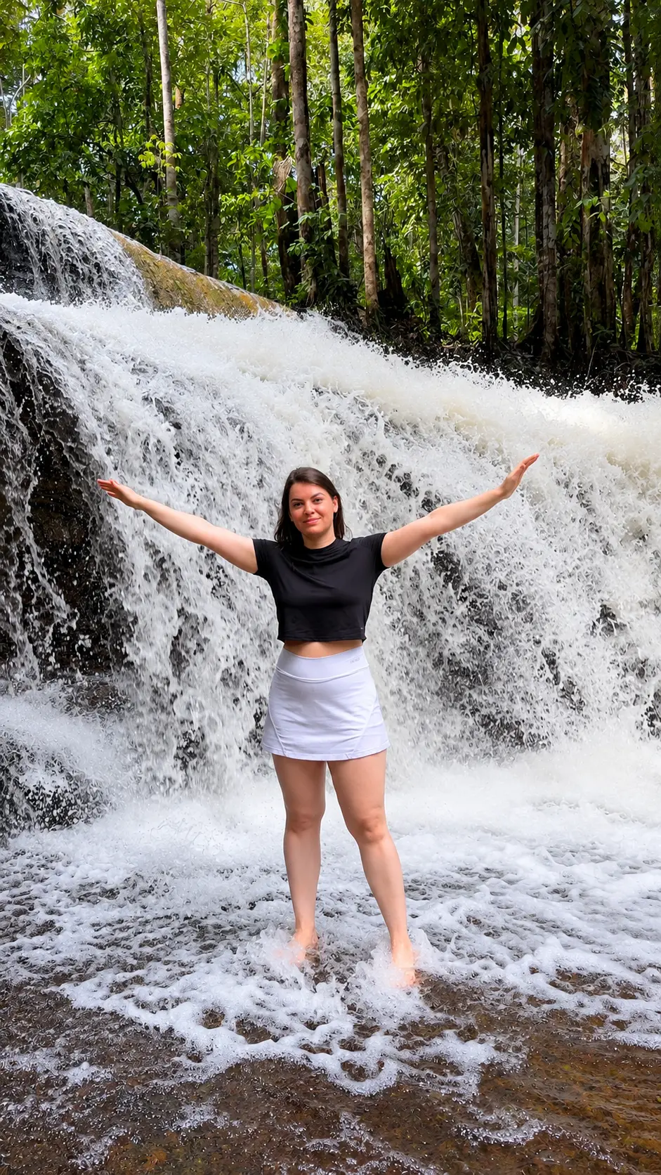 Cachoeira caindo em poço de água cristalina cercado por floresta