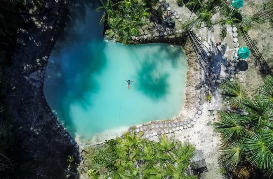 Lagoa azul intensa com areia clara e palmeiras ao redor