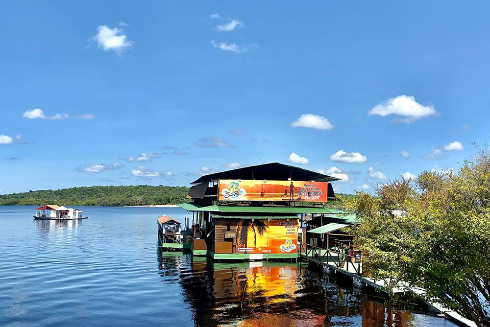 Restaurante flutuante de madeira sobre o rio cercado pela floresta