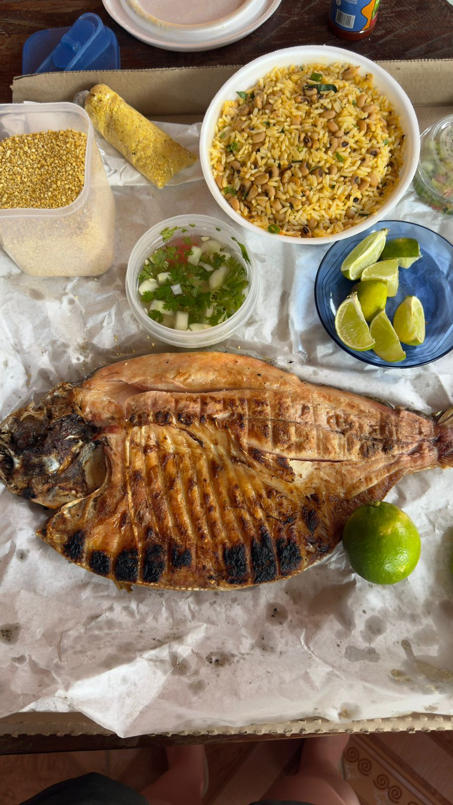 Peixe grelhado servido com arroz, farinha e limão em mesa de madeira